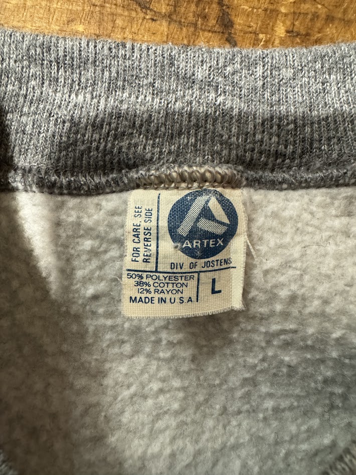 ARTEK DIV. OF JOSTENS タグの接写。50%POLY/38%COTTON/12%RAYON・Made in U.S.A. 表記。