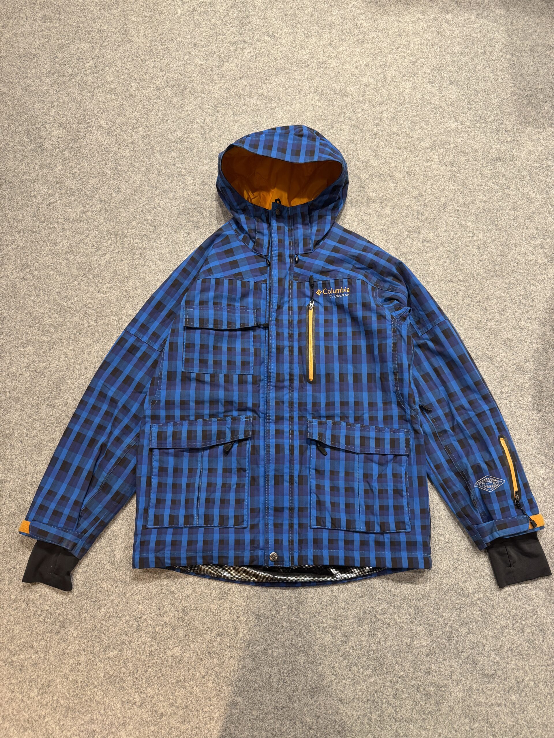 グレーの床に平置きしたColumbia Titanium ブルーチェックジャケット