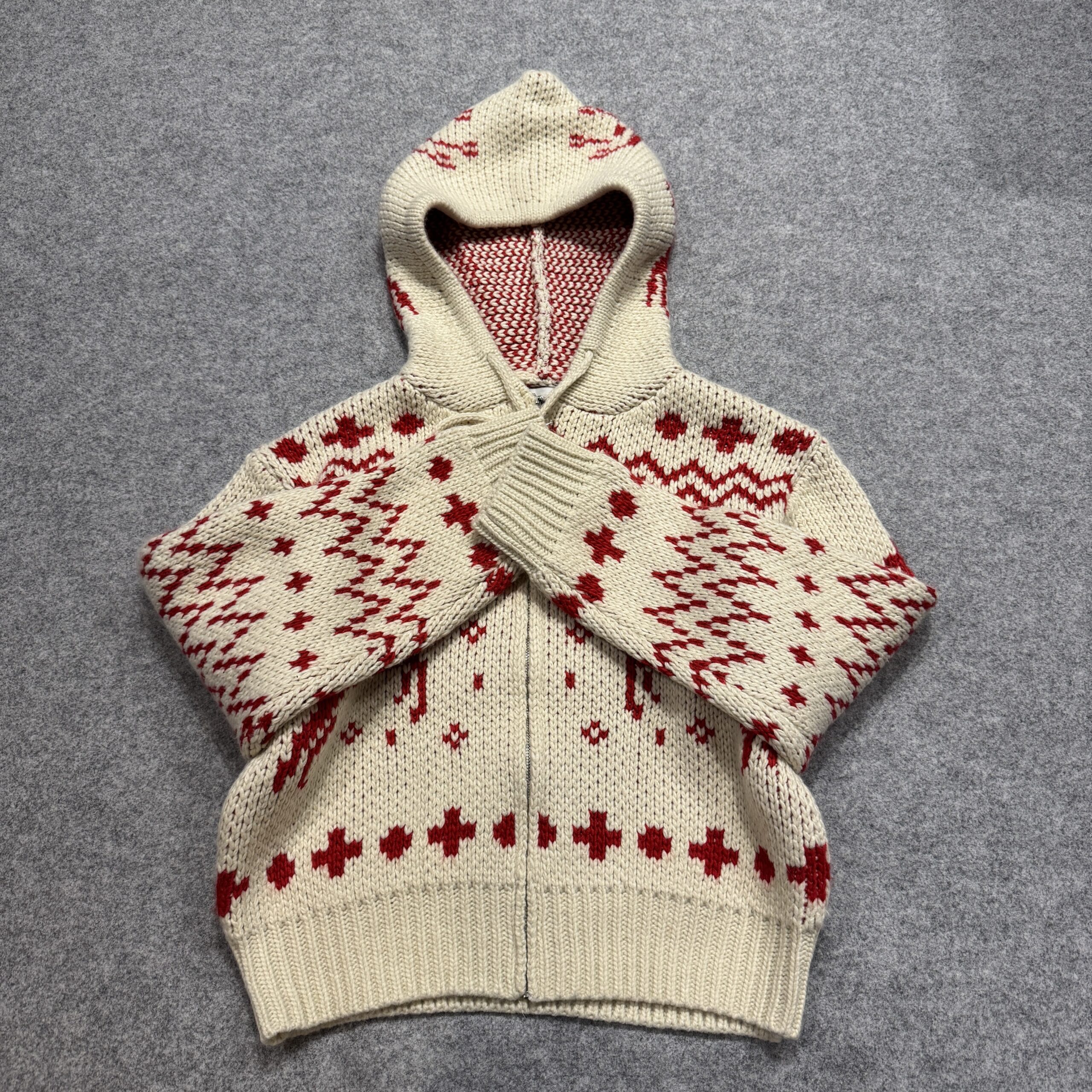 トナカイ柄フルジップニットパーカーを袖をクロスさせて平置きにした様子。ニットのふっくら感とほっこりした雰囲気が伝わる。