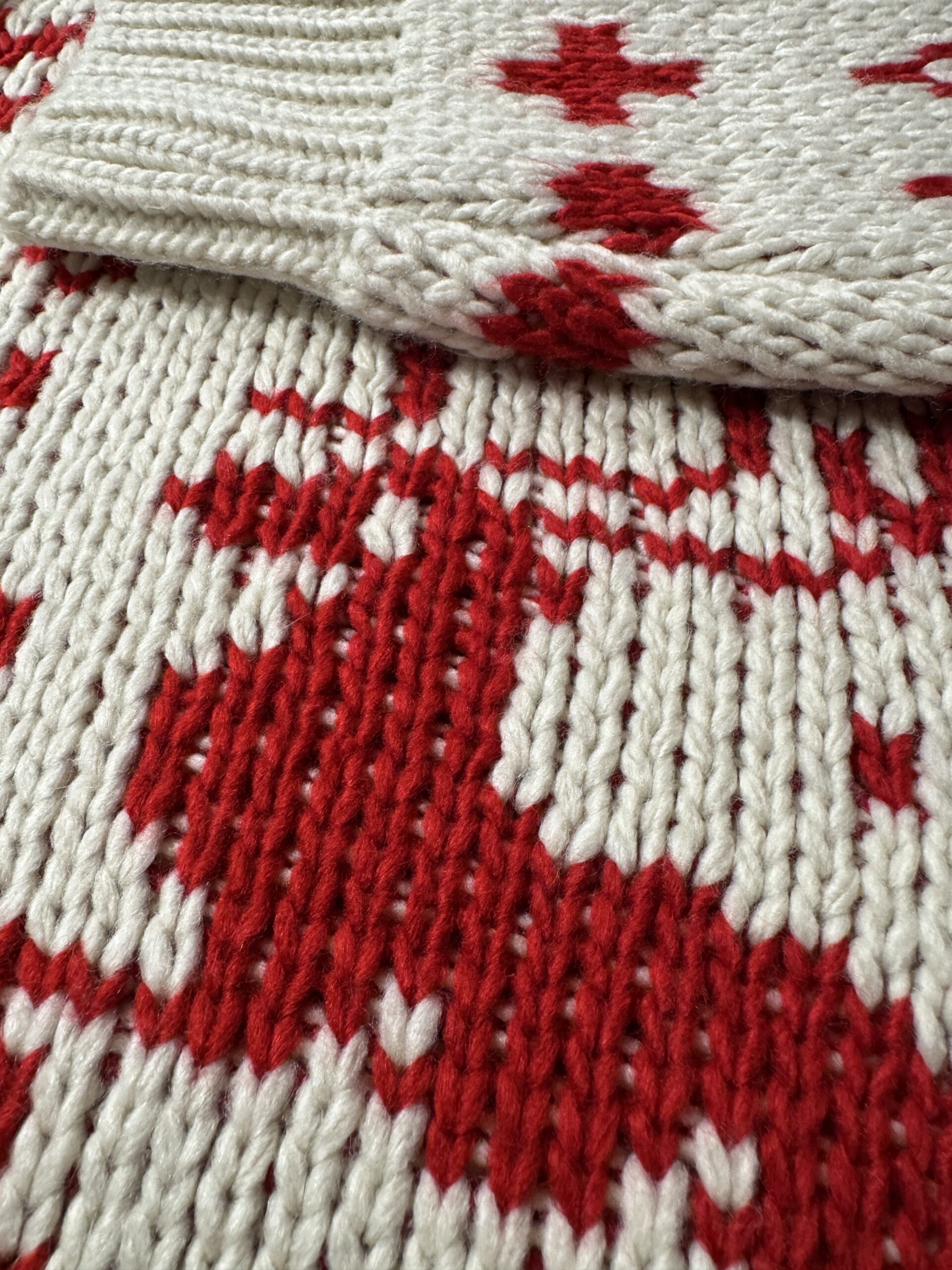 トナカイ柄部分と袖リブの編み目アップ。太めの毛糸で編まれた赤いトナカイと、しっかりとしたリブが冬らしい表情を見せる。