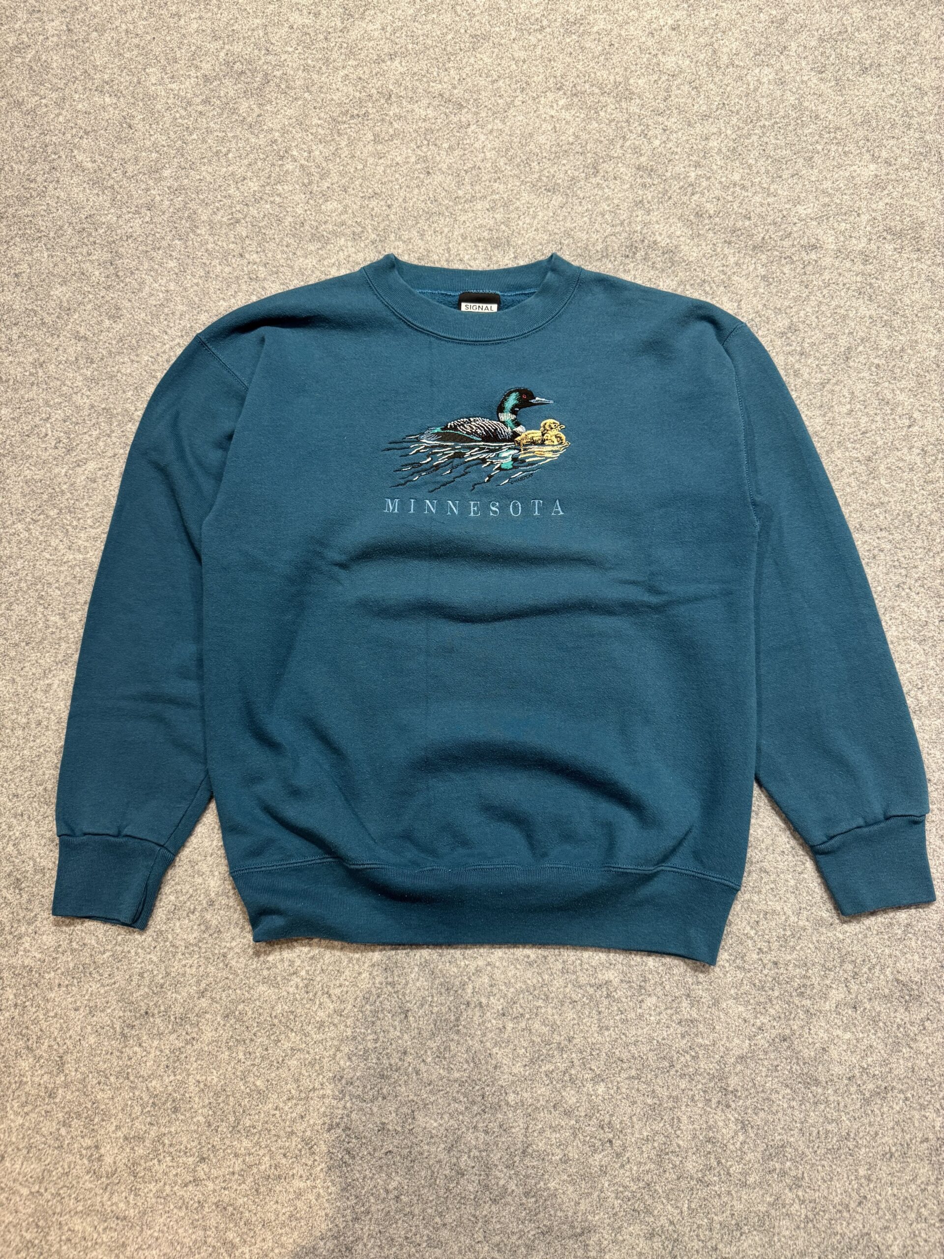 Signal SportボディのMINNESOTA刺繍スウェットの正面。ブルーグリーンのボディにルーン親子の刺繍が映える一枚。