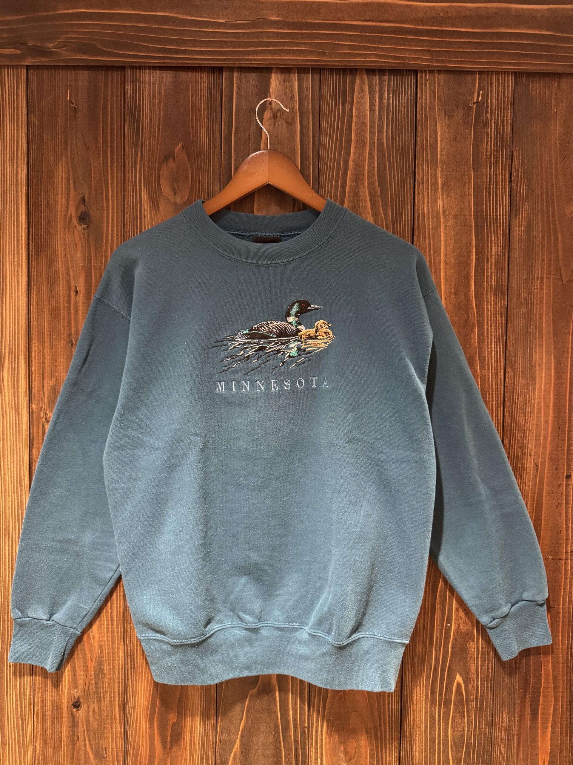 Signal SportボディのMINNESOTA刺繍スウェット。深いブルーグリーンの色味とルーンの親子刺繍が印象的な一枚。