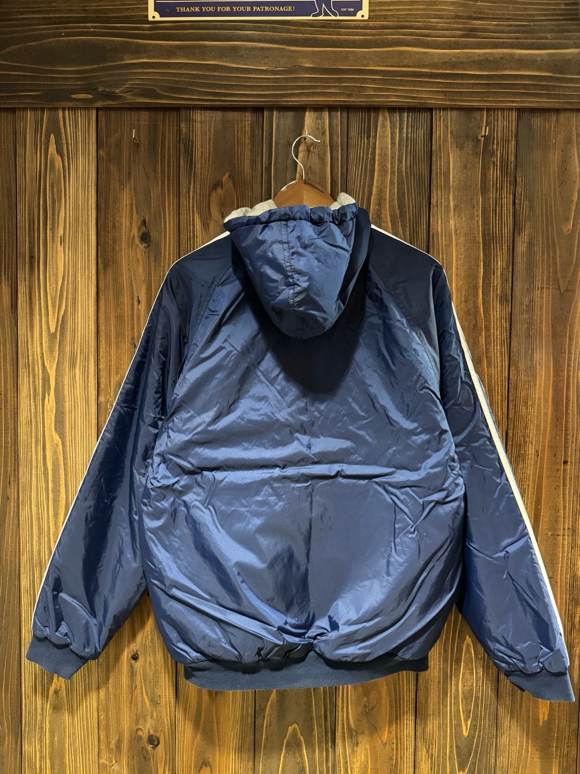 ネイビーのナイロン面を表にしたアディダスリバーシブルフーディのバックスタイル。無地でシンプルなデザイン。