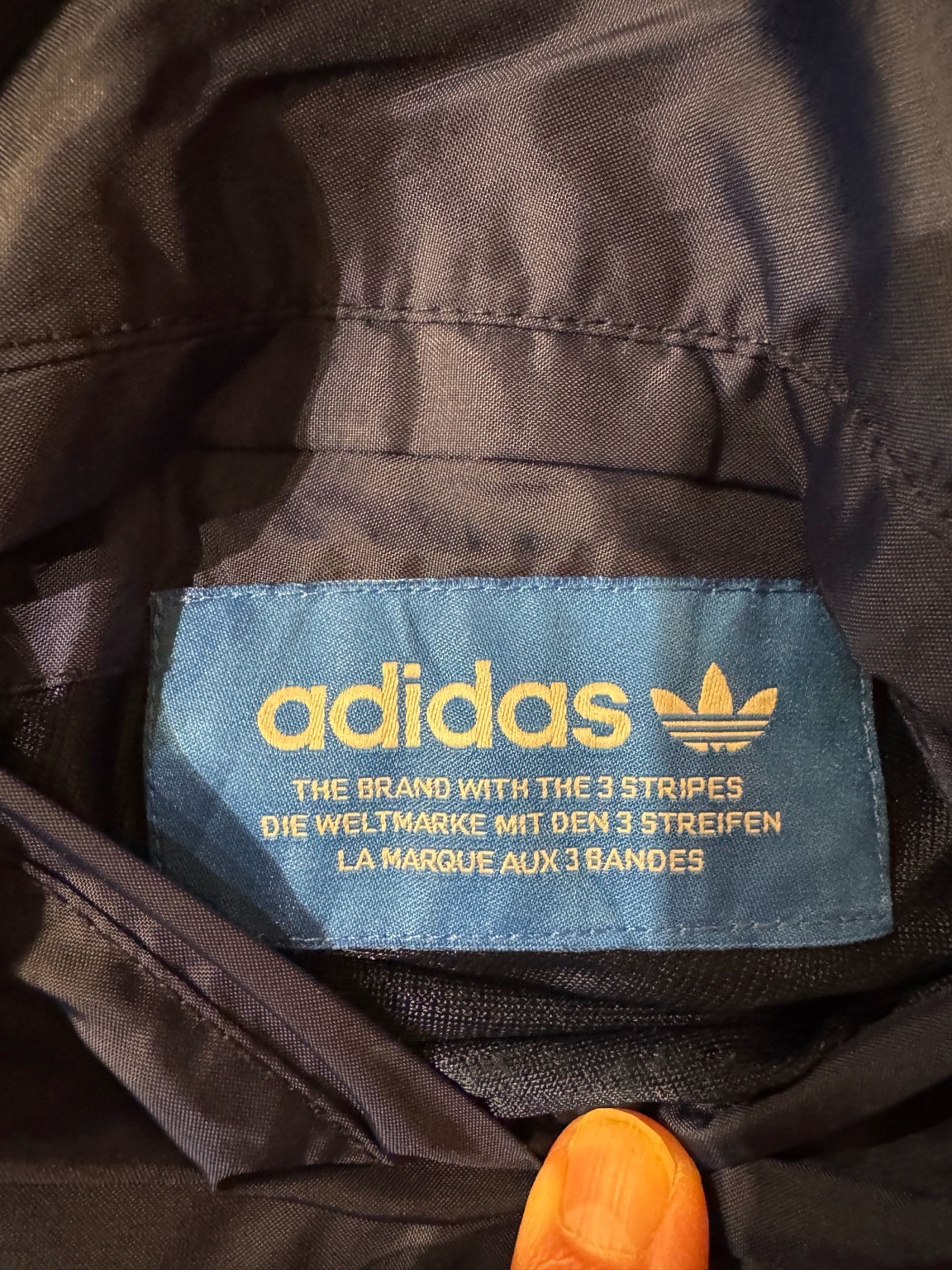 アディダスオリジナルスの青タグ。THE BRAND WITH THE 3 STRIPESと3か国語表記が入っている。