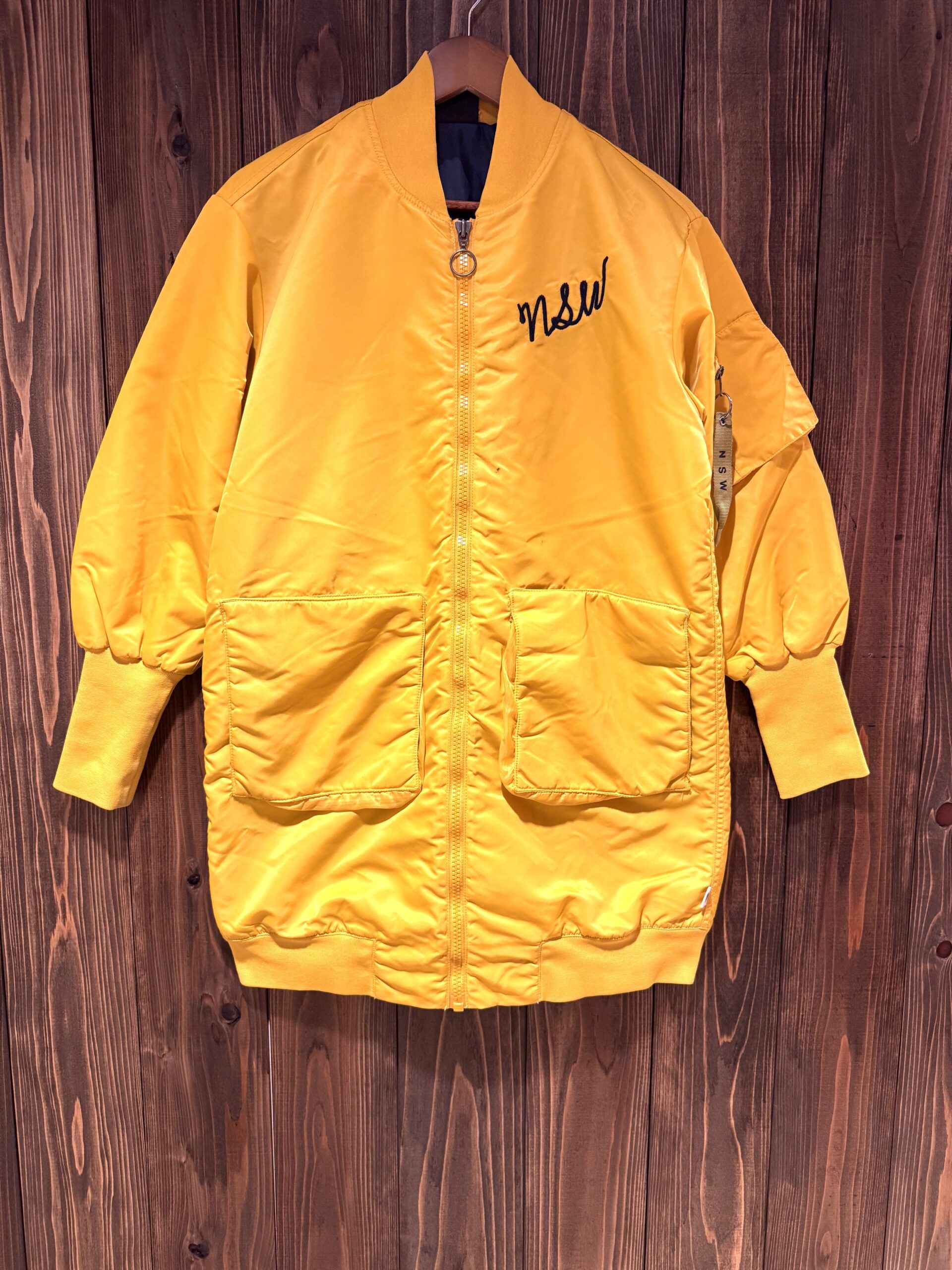 NIKE NSW ロング丈ナイロンジャケット 前面（マスタードイエロー）