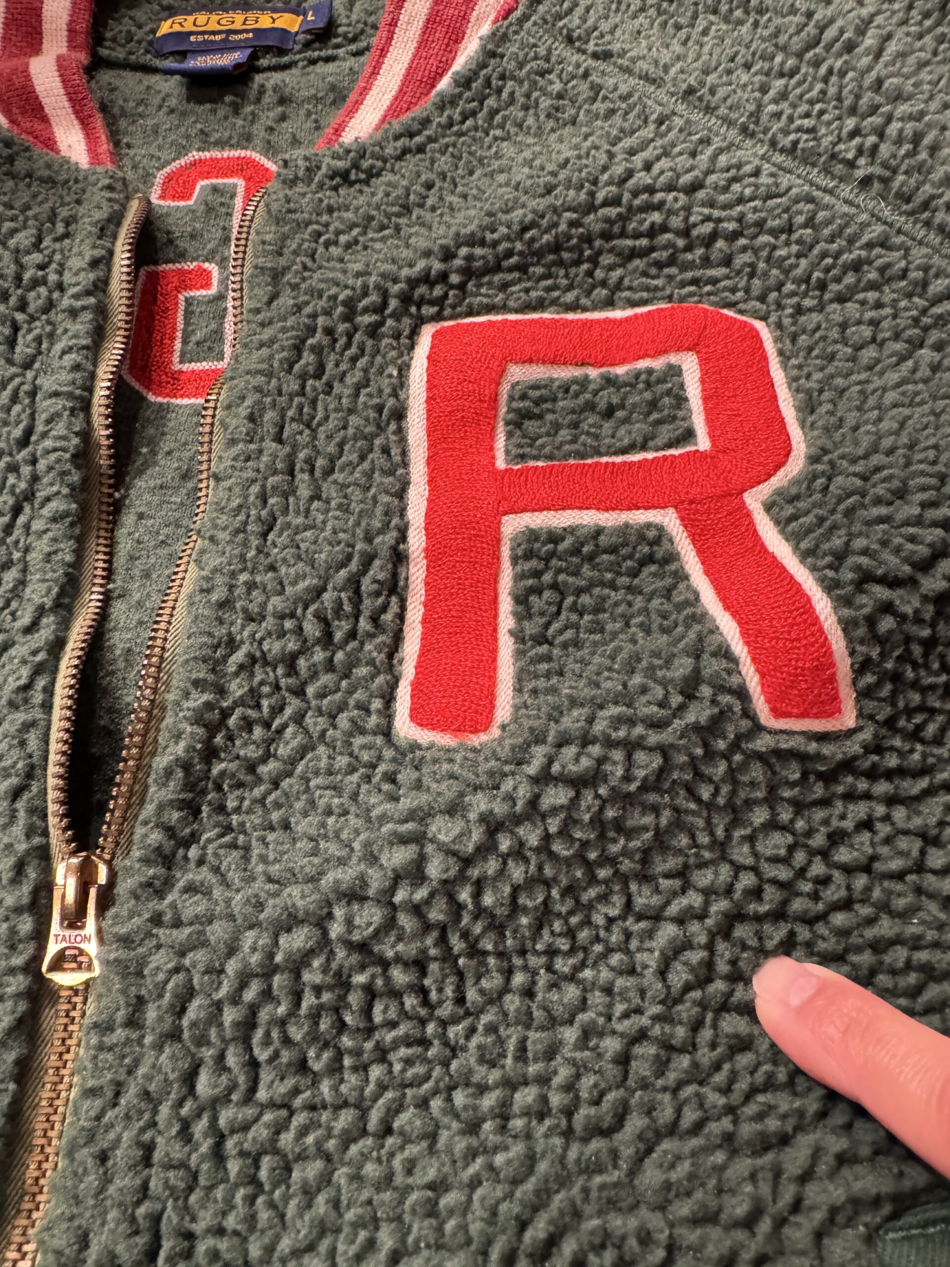 ボアの質感とRワッペン、前立てジップ周りのディテールが分かるアップ画像。