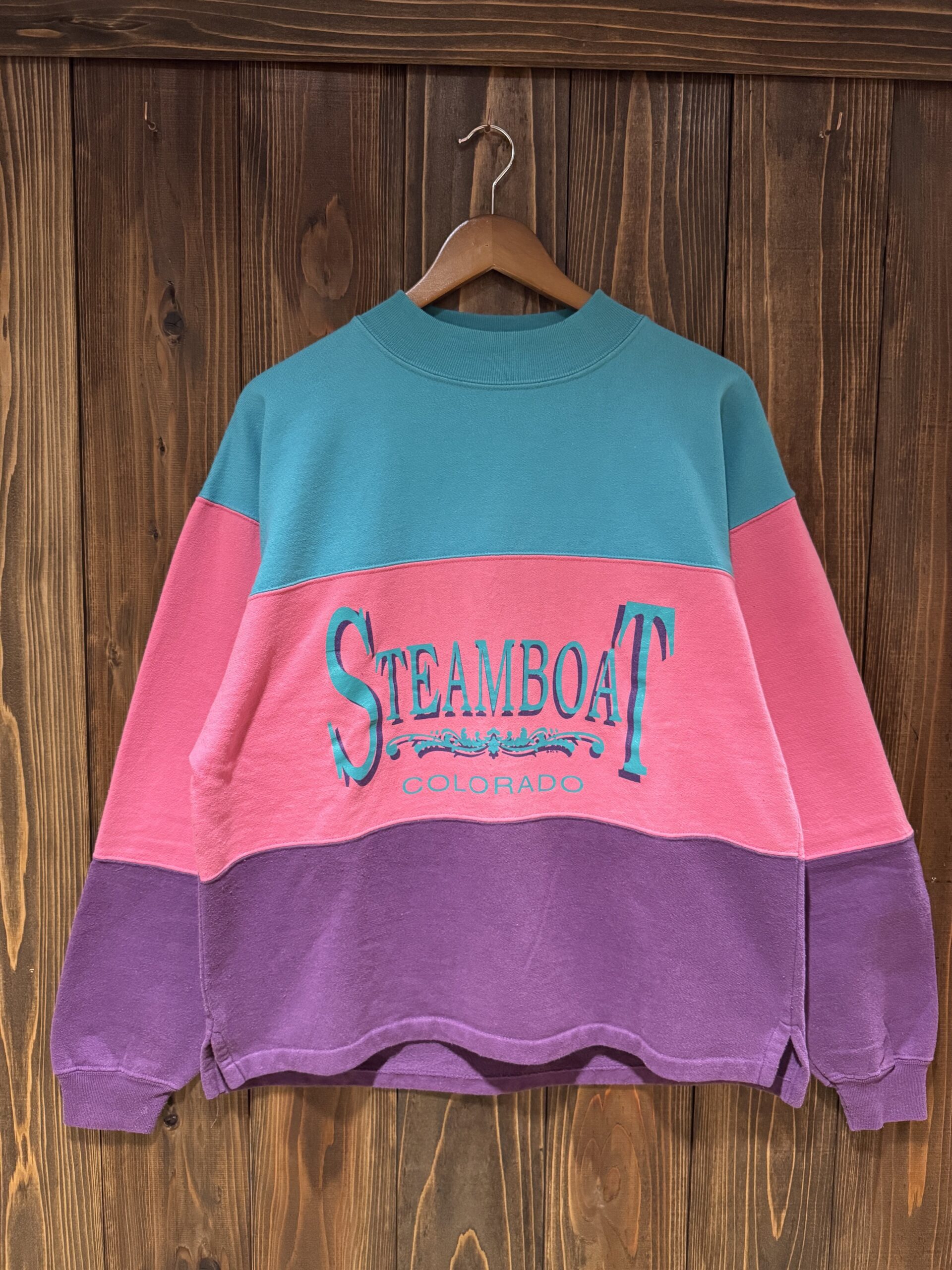 ターコイズ×ピンク×パープルの3色切り替えが可愛い、STEAMBOAT COLORADOロゴ入りAloreスウェットのフロント（ハンガー掛け）。